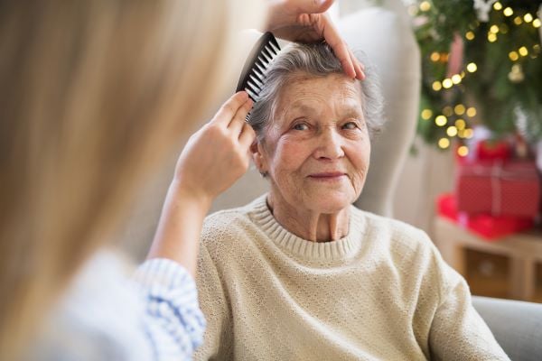 In home care assistant brushing a residents hair