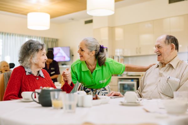 Staff member talking to two aged care residents at table