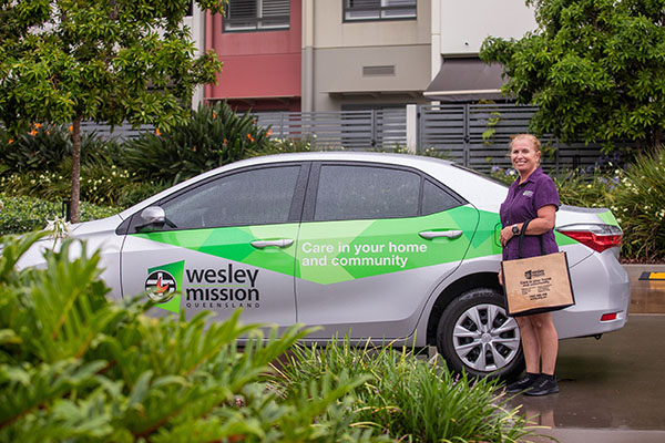 Image representing jobs and careers at Wesley Mission Queensland, Brisbane. It shows staff by a WMQ car used for transport services and home care support such as grocery and shopping