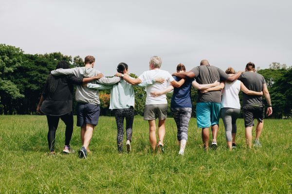 Group of people with arms around each other in field