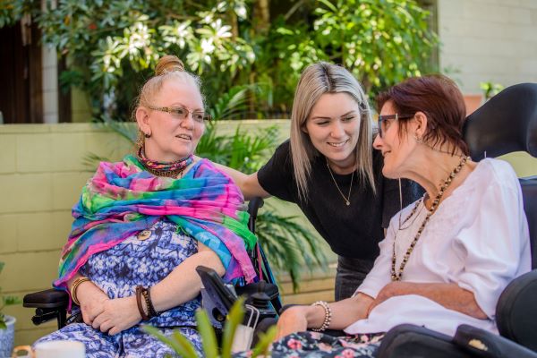 Staff talking to two retirees in one of our specialist disability apartments in Brisbane