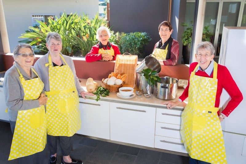 people-wearing-bright-aprons-cooking-soup