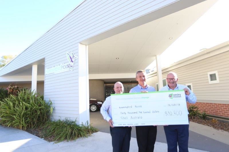 three-people-smiling-holding-large-cheque