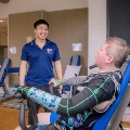 Man using gym equipment while therapist looks on