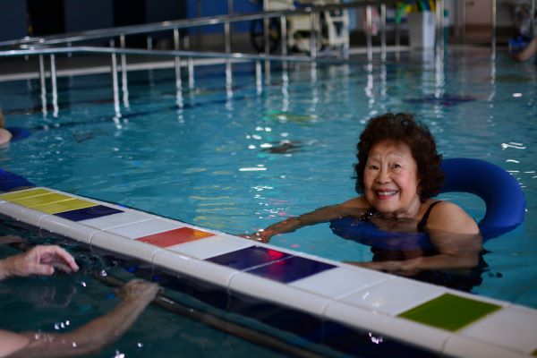 Lady smiling in pool while wearing flotation equipment