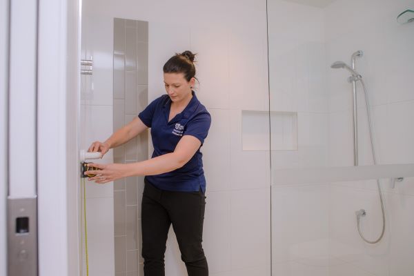 Therapist using tape measure to measure height of grab rail in bathroom