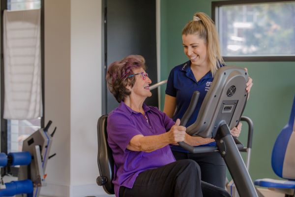 Staff member speaks to client on exercise machine