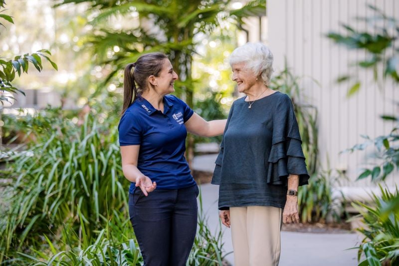 Staff member and older lady standing smiling in garden