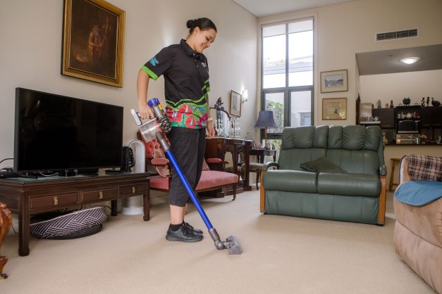 Lady vacuuming a lounge room with hand held vacuum