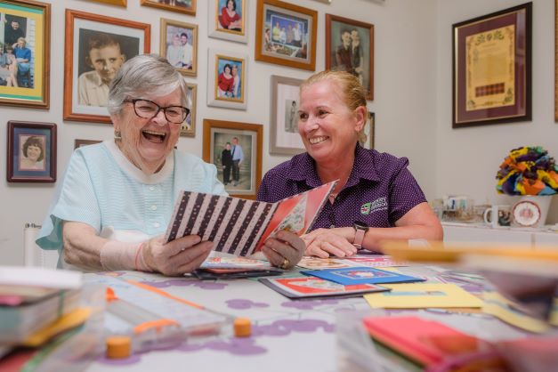 Elderly lady smiling with a WMQ staff member as they look at cards