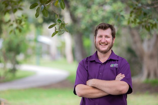 Male WMQ staff member in purple shirt smiling