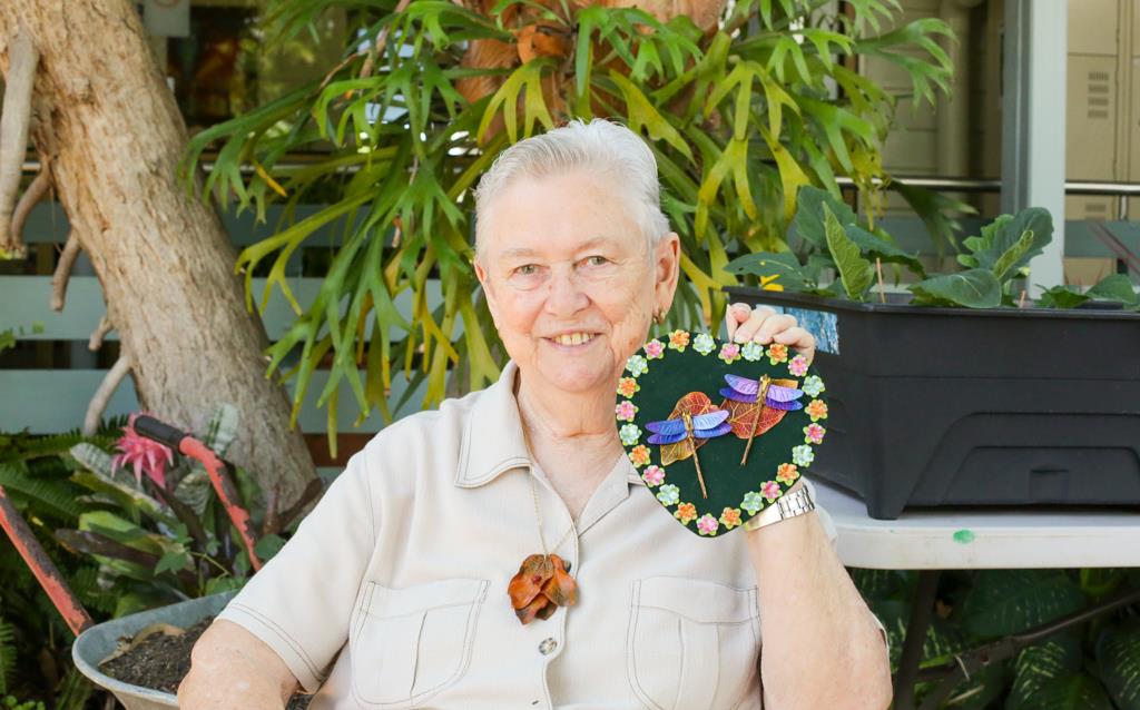 Lady smiles while holding handmade leather goods