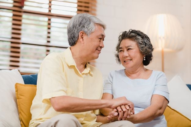 Elderly couple holding hands whilst seated