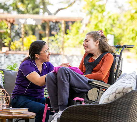 Worker and teenager smiling in the garden of Hummingbird House, Queensland’s only children’s hospice