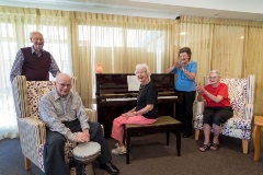 Residents enjoy a social get together around the piano