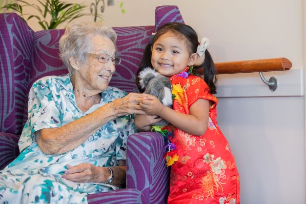 Young girl showing a stuff toy to elderly lady