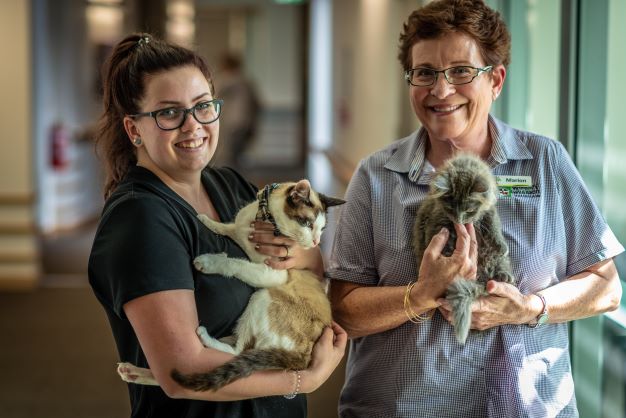 Two staff members smiling and holding Eden cat pet companions
