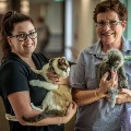 Two staff members smiling and holding Eden cat pet companions