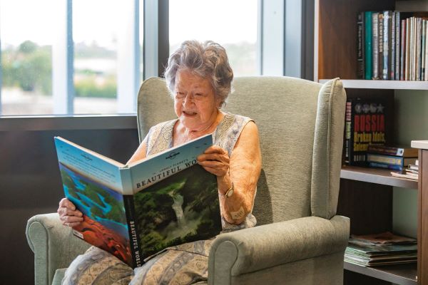 Resident reading peacefully in armchair by window at Dovetree