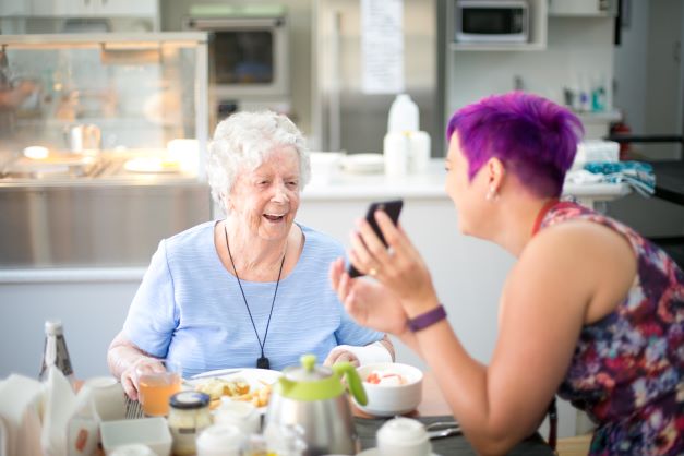 Resident and staff member during a meal in Jacobs Court, one of our residential aged care communities in Brisbane