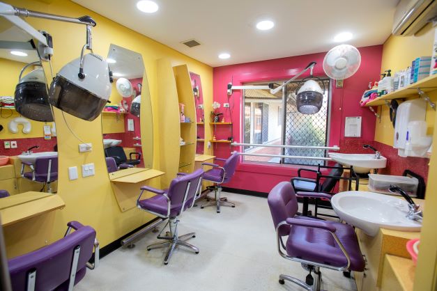 Hairdressingsalonwithpinkandyellowwallschairsandstations