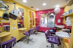 Hairdressing salon with pink and yellow walls, chairs and stations