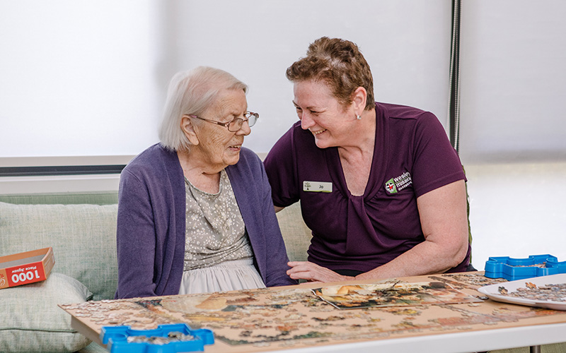 WMQ aged care worker plays puzzle with a resident