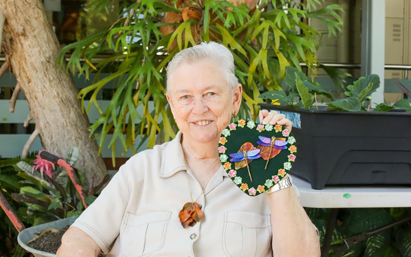 Retiree shows a love heart craft at Wesley Mission Queensland aged care respite centre