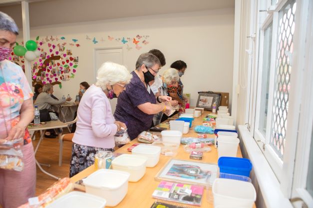 Ladies collecting their craft supplies from a table