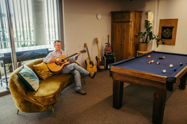 Man sitting with guitar in pool room