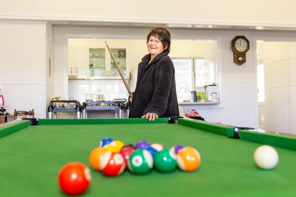 Lady smiling at pool table with balls in foreground