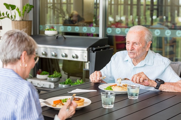 A lady and gentlemen sitting at a table eating a light lunch