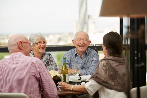 Group of retirees enjoy balcony with wine and food
