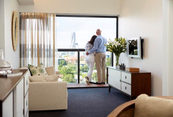 Aldersgate offers expansive views Couple enjoying expansive views of Brisbane skyline from an apartment at Aldersgate retirement village, in Red Hill, Brisbane