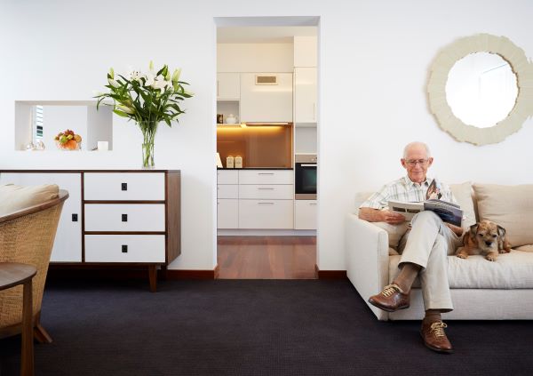 Resident sitting in his living room with his dog at Aldersgate