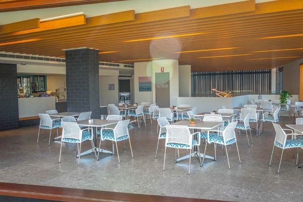 White tables and chairs in large indoor-outdoor cafe