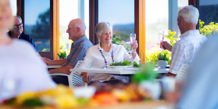 Couple sitting down at a cafe to a meal and raising their glasses