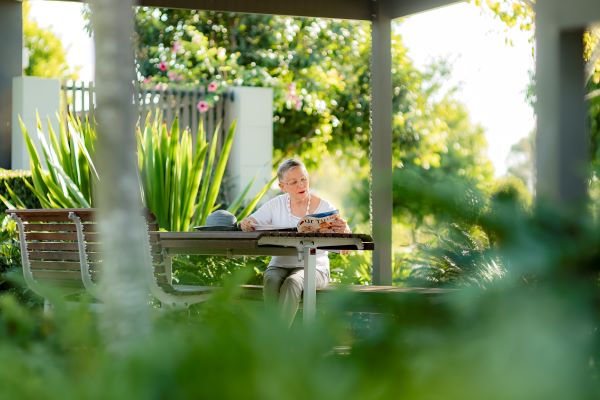 Resident reading in the gardens at Wheller on the Park