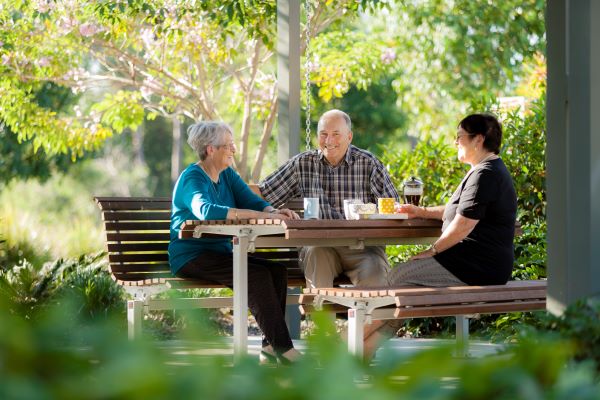 Residents at a picnic table at Wheller on the Park retirement village surrounded by trees