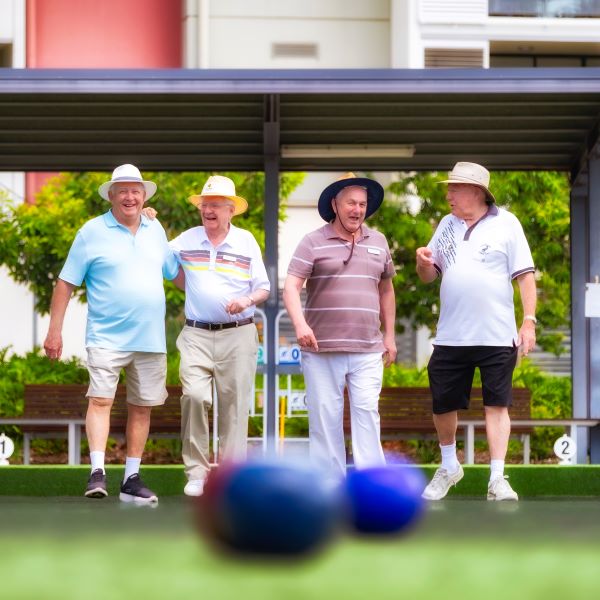 Group of men play lawn bowls