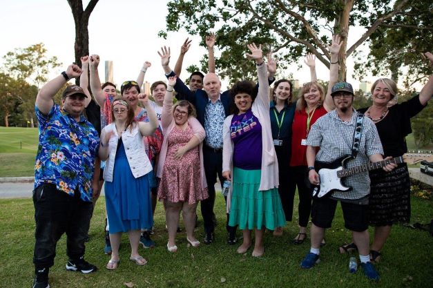 A musical group outdoors with their hands up