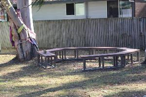 Outdoor seats in a circle on grass with tree nearby