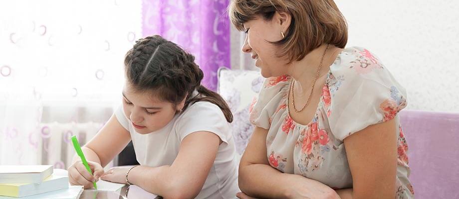 A mother and school aged daughter writing