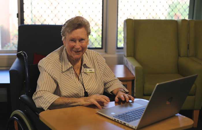 Older woman in wheelchair sitting with computer