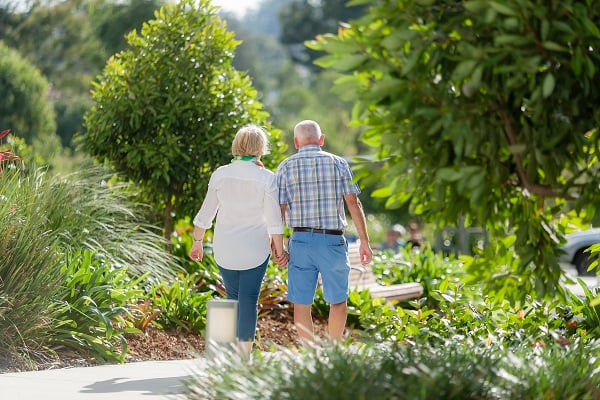 Couple walking away from camera through garden