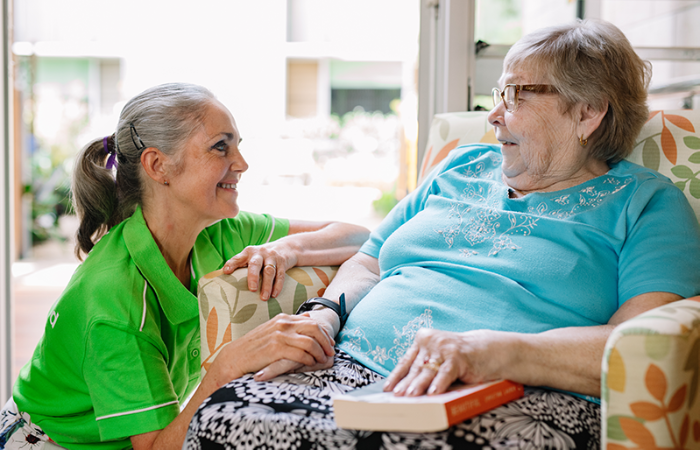 woman in uniform holding hands supportively with older womans