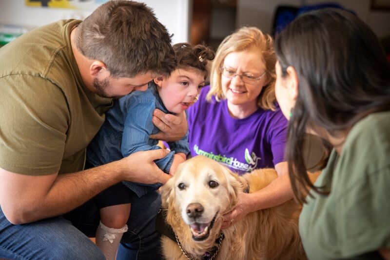 people helping sick child pat dog